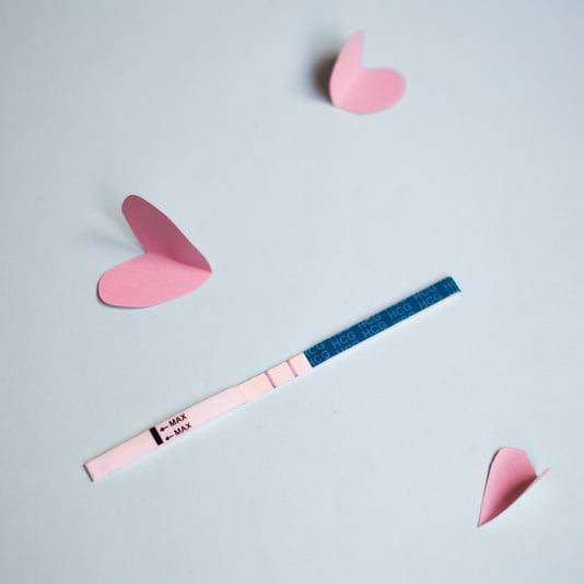 Positive pregnancy test with two strips and pink hearts. blue background, copy space