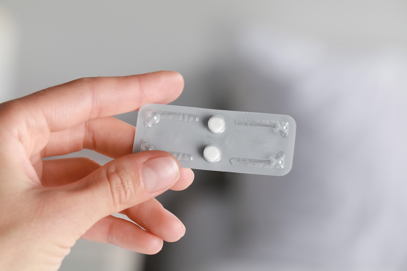 Woman Holding Blister of Emergency Contraception Pills on White