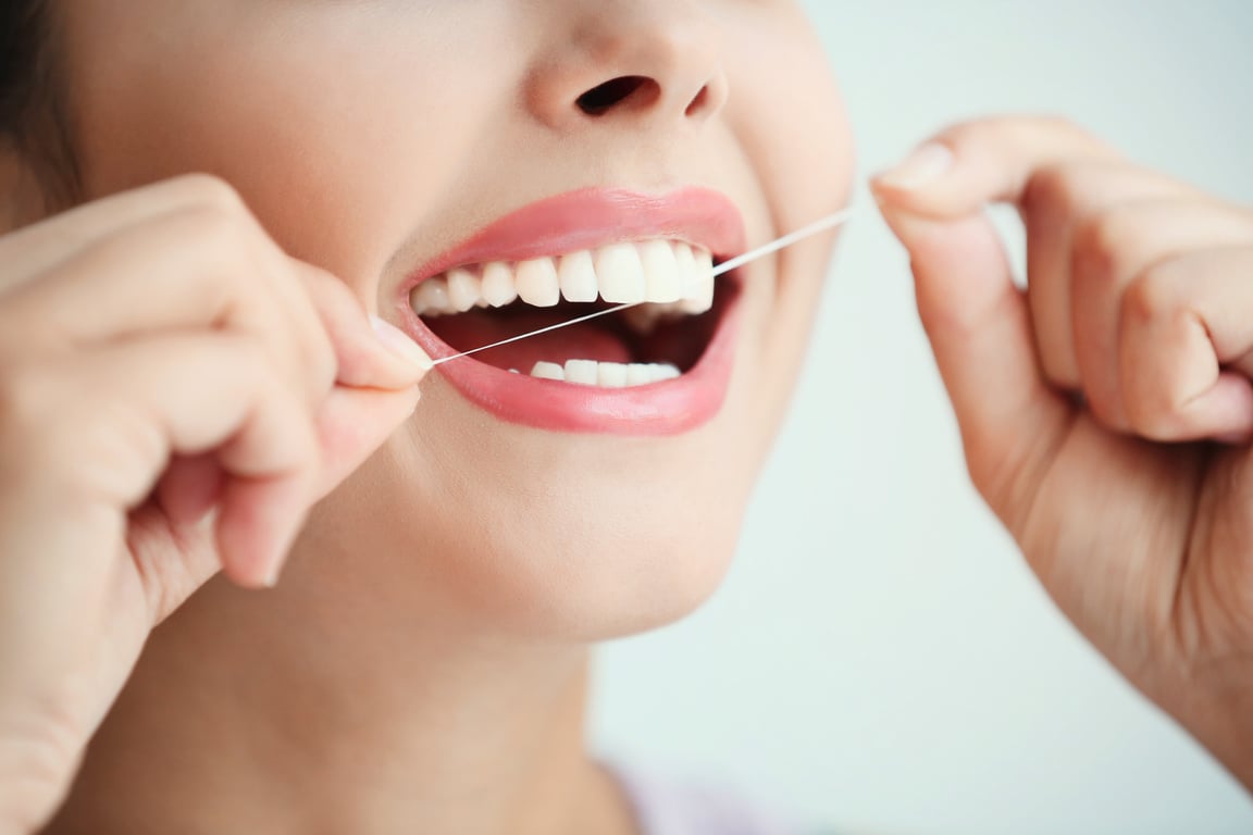 Young Woman Cleaning Teeth with Dental Floss